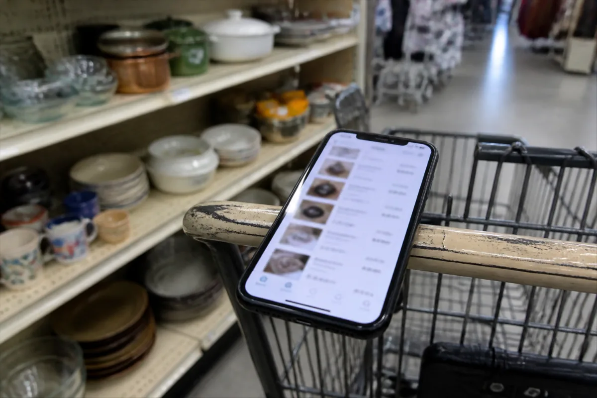 Phone showing recent sold prices on a thrift store cart handle